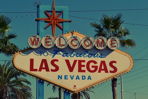 a sign in front of a palm tree with Welcome to Fabulous Las Vegas sign in the background