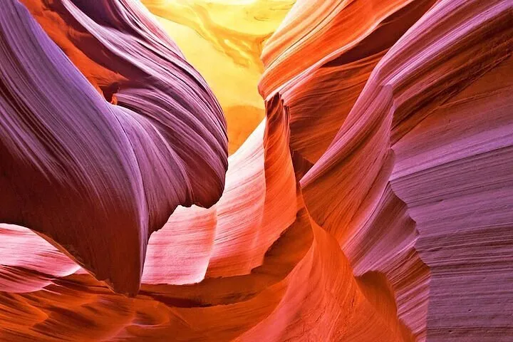 Colorful sandstone formations with wavy patterns illuminated by sunlight.